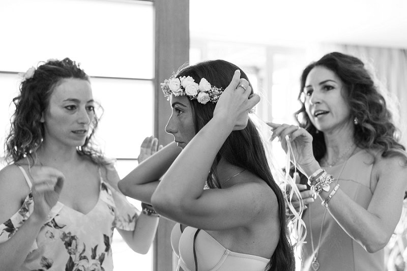Black and White Image of Bride Putting on Her Flower Crown in Her Suite at Ionian Blue