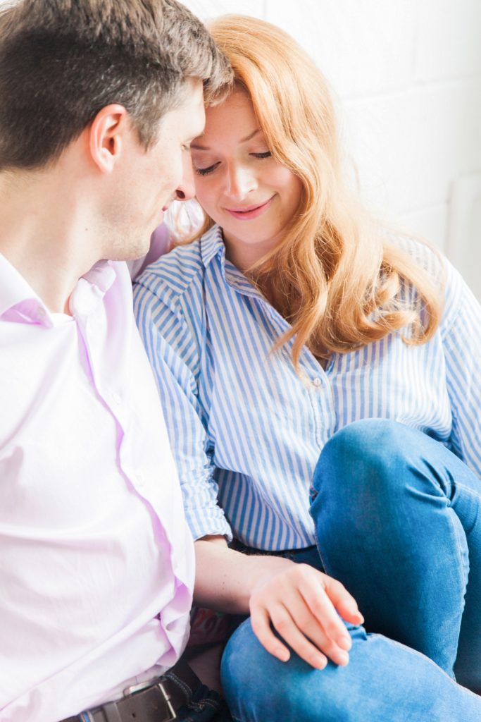 Couple cuddle up on the couch during their at home engagement session in London