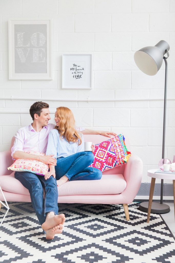 Couple snuggle on the couch during their at home engagement session