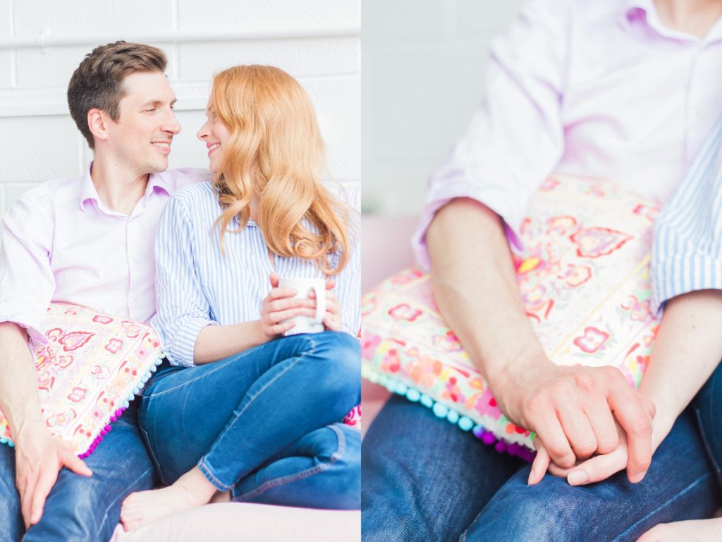 Coule chat while holding hands on the couch during their engagement shoot