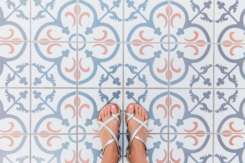 Feet in Sandals Against Blue White and Terracotta Tiles in Oia Santorini