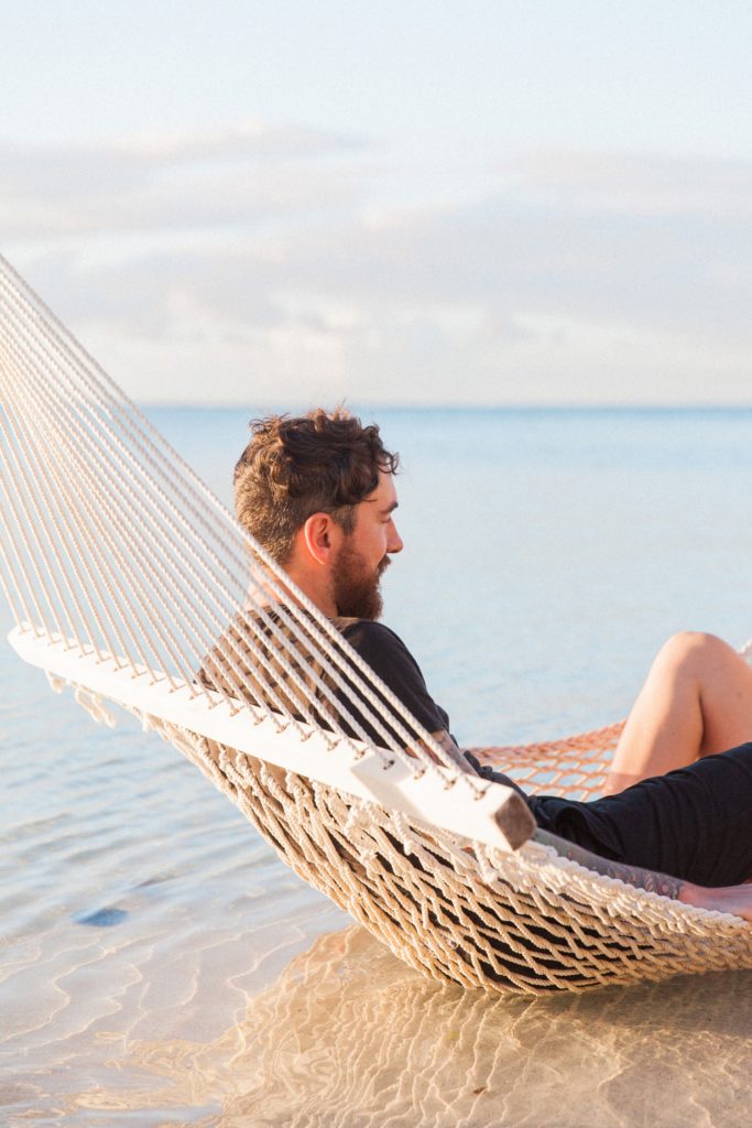 Groom to be relaxing in a sea hammock during his Mauritius engagement session