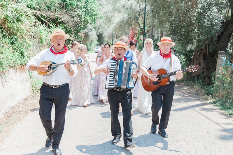 Trio of Greek musicians in full song as they serenade the bridal party to the ceremony