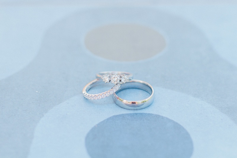 Brides three stone diamond engagment ring, eternity band and the grooms ring on blue tiles