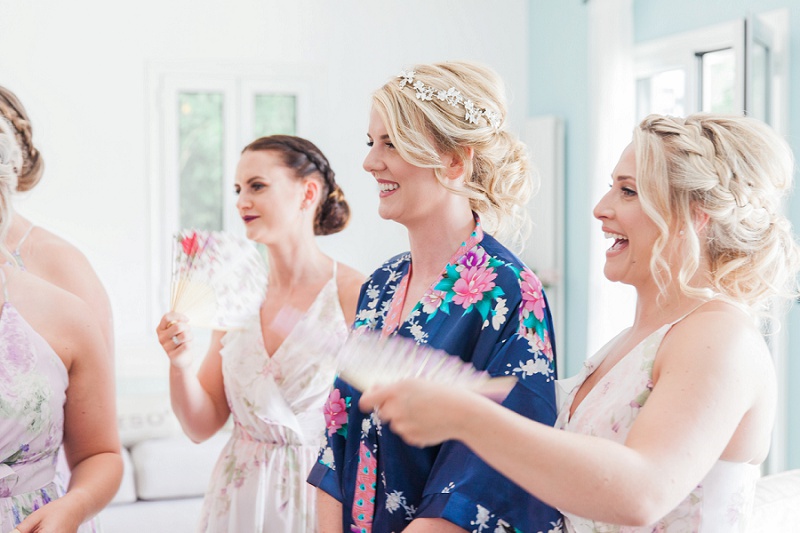 Smiling bride being fanned by her bridesmaids before she gets into her dress