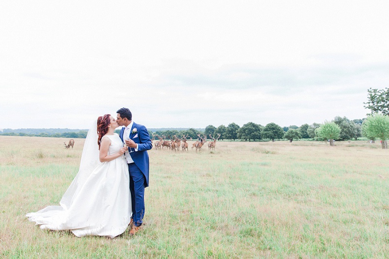 Bride and Groom Kissing in Richmond Park with Deer Behind Them