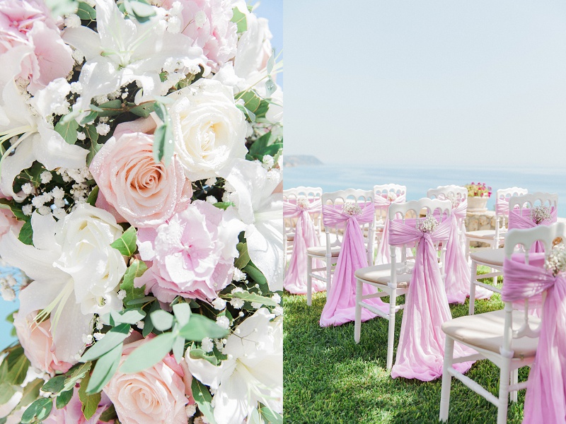 Close up of the pink and white floral arch and decorated white chairs with a view of the Ionian Sea.