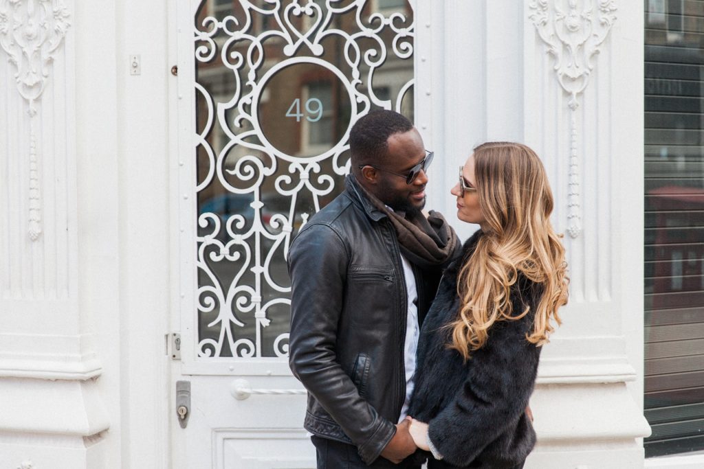Stylish couple hold hands in front of a white shop front in Marylebone