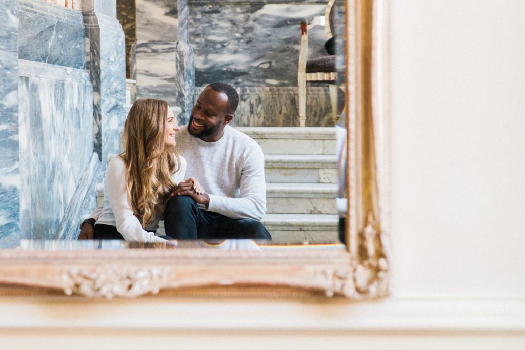 Image taken in a mirror of an engaged couple smile at eachother