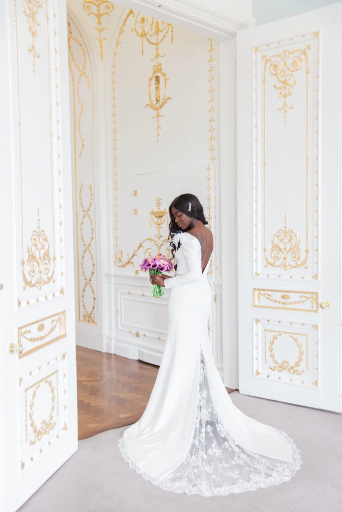 Black bride poses with a purple dahlia and cala lily and coral rose bouquet at her 10-11 Carlton House Terrace wedding