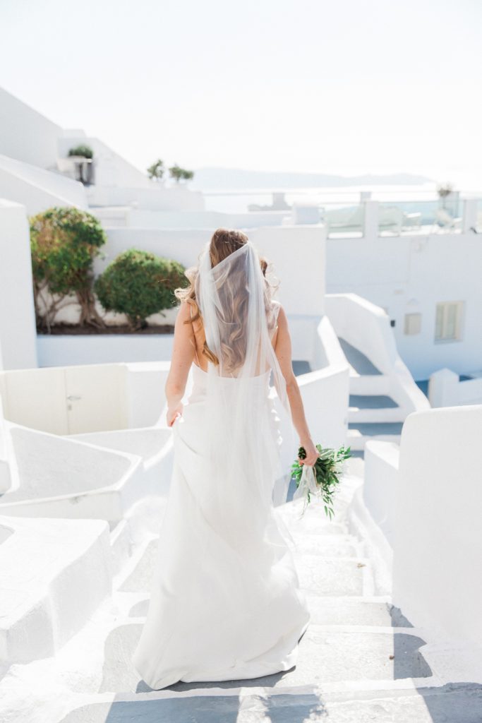Bride makes her way down the stairs to her elopement ceremony at Dana Villas Santorini