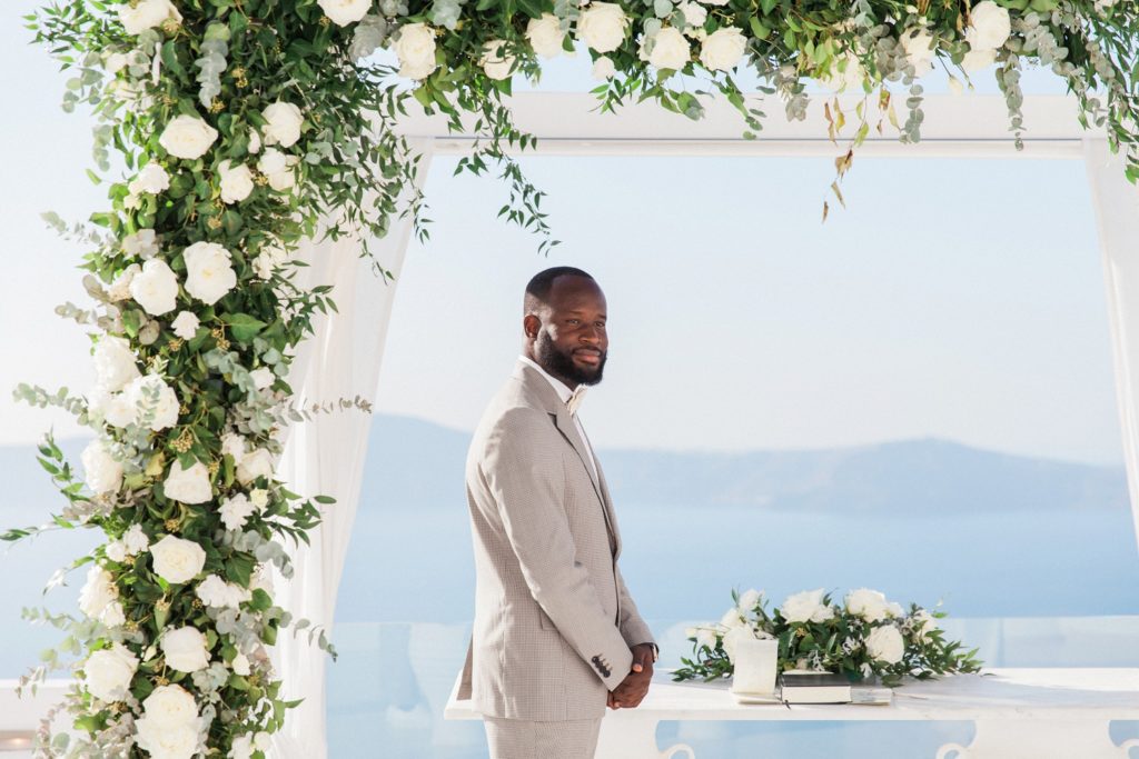 Grooms smiles as his bride arrives at their elopement ceremony in Santorini