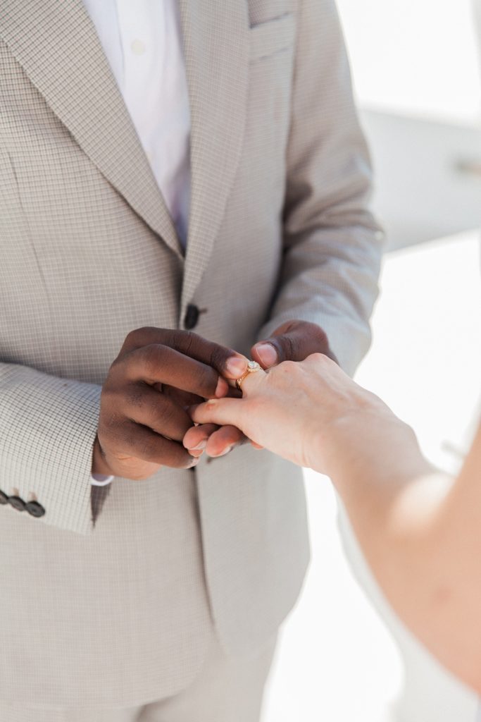 Close up of the groom placing a ring on her brides finger during their elopement in Santorini
