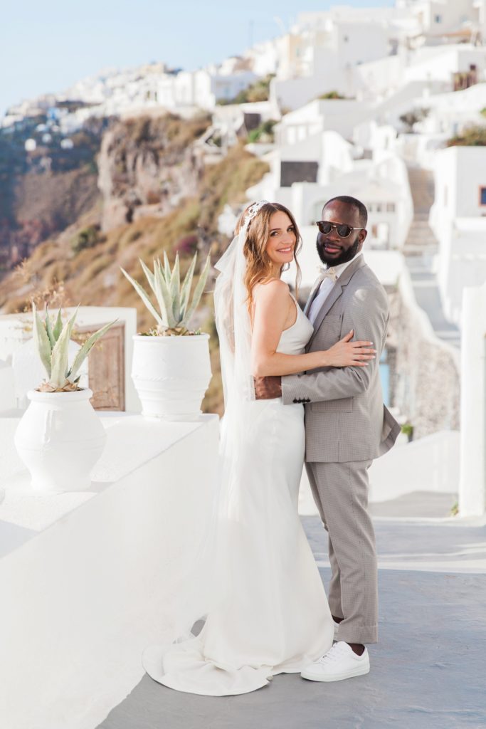 Bride and groom smile on the streets of Santorini after their elopement