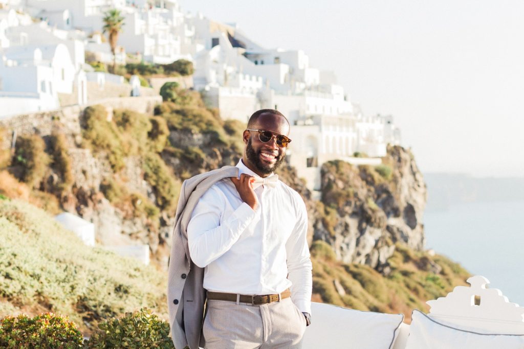 Portrait of a happy groom against the Santorini houses and the cliffs
