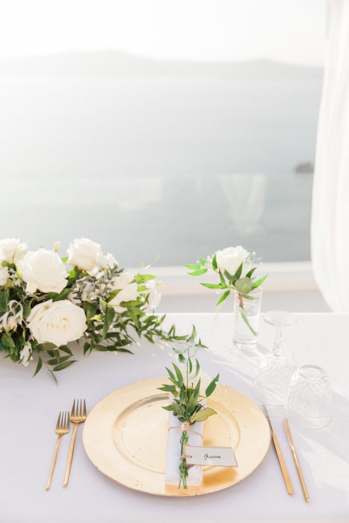 White and gold elopement table setting with a view across the caldera in Santorini