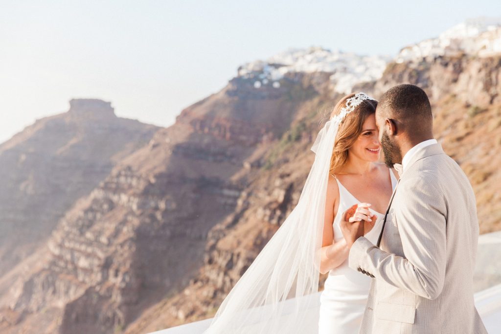 Bride and groom dance with a backdrop of Skaros Rock in Santorini