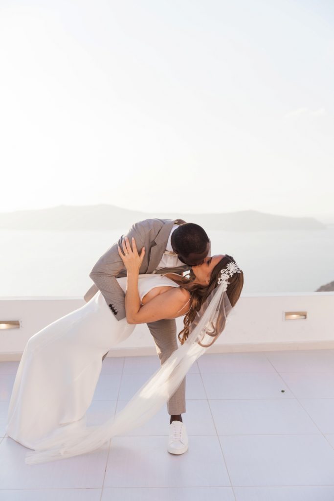Groom kisses his bride as he dips her during their first dance at their Santorini elopement