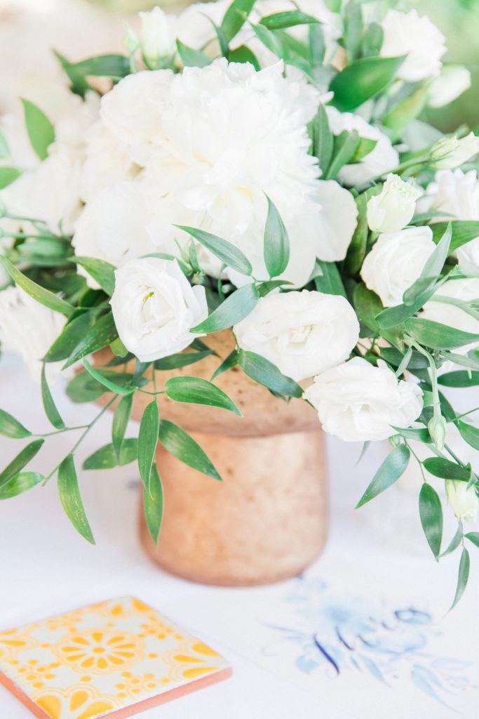 White and green floral centrepieces in copper vases at Emelisse Hotel wedding venue on Fiskardo