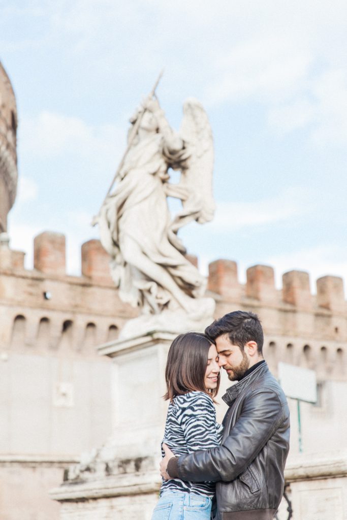 Romantic couple in front of one of the Castel Sant'Angelo angels in Rome