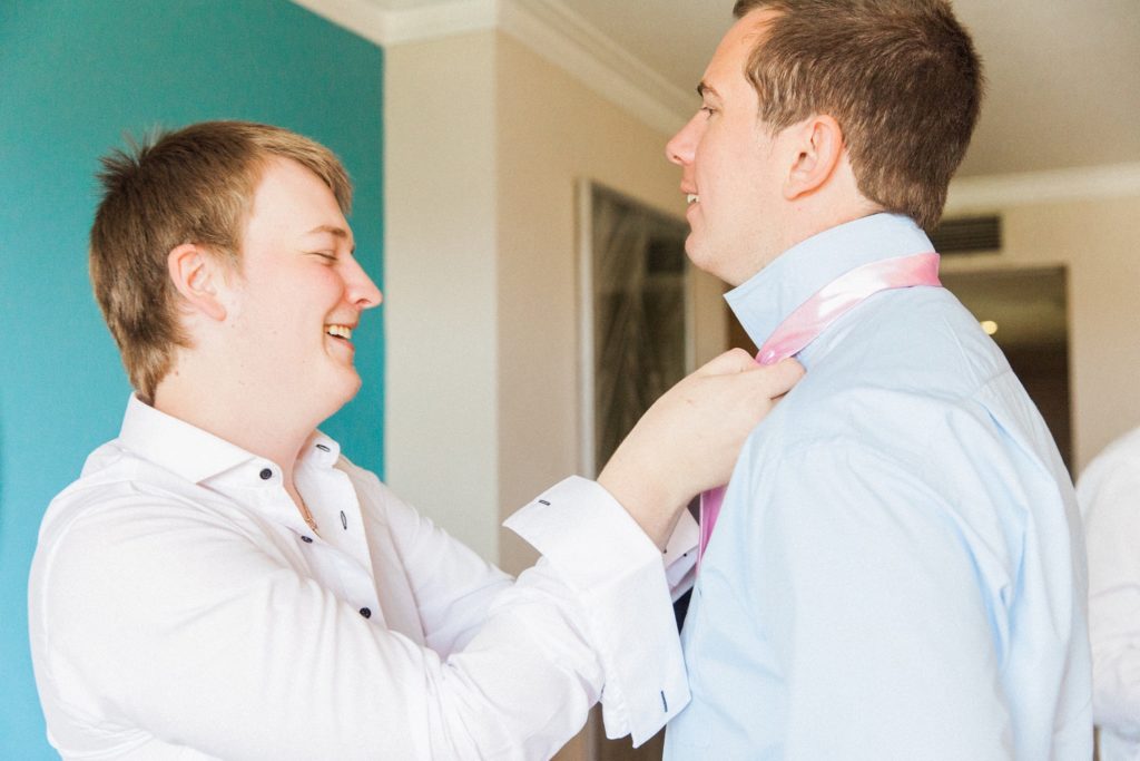 Groom helps one of his groomsmen get dressed on the morning of his Egypt wedding