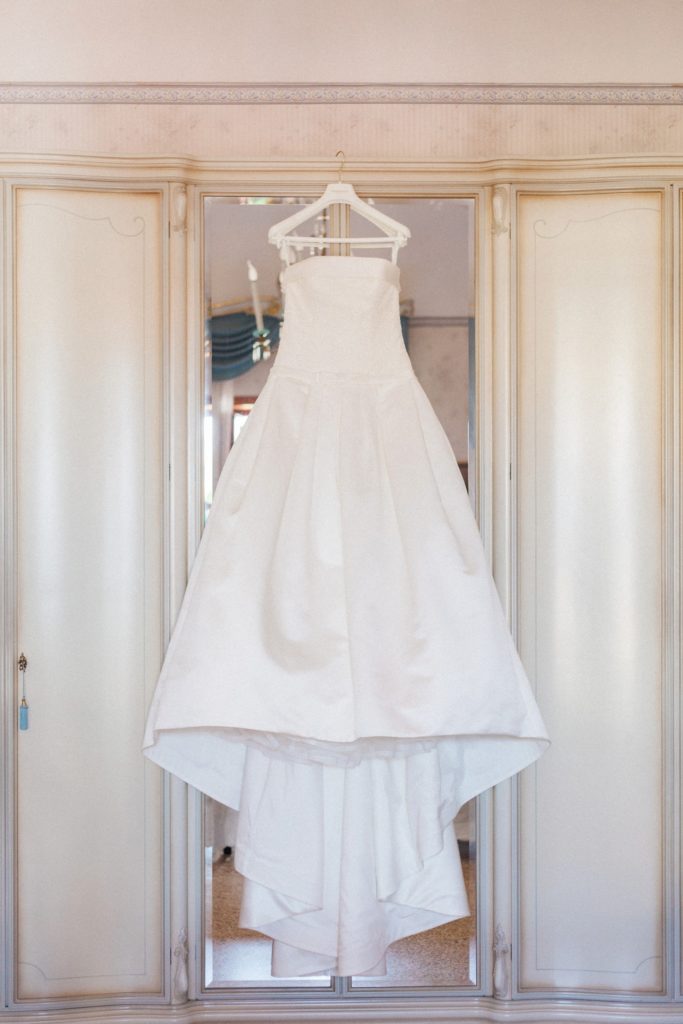 Italian brides beautiful white Pronovias gown hanging in her bedroom on the morning of her wedding