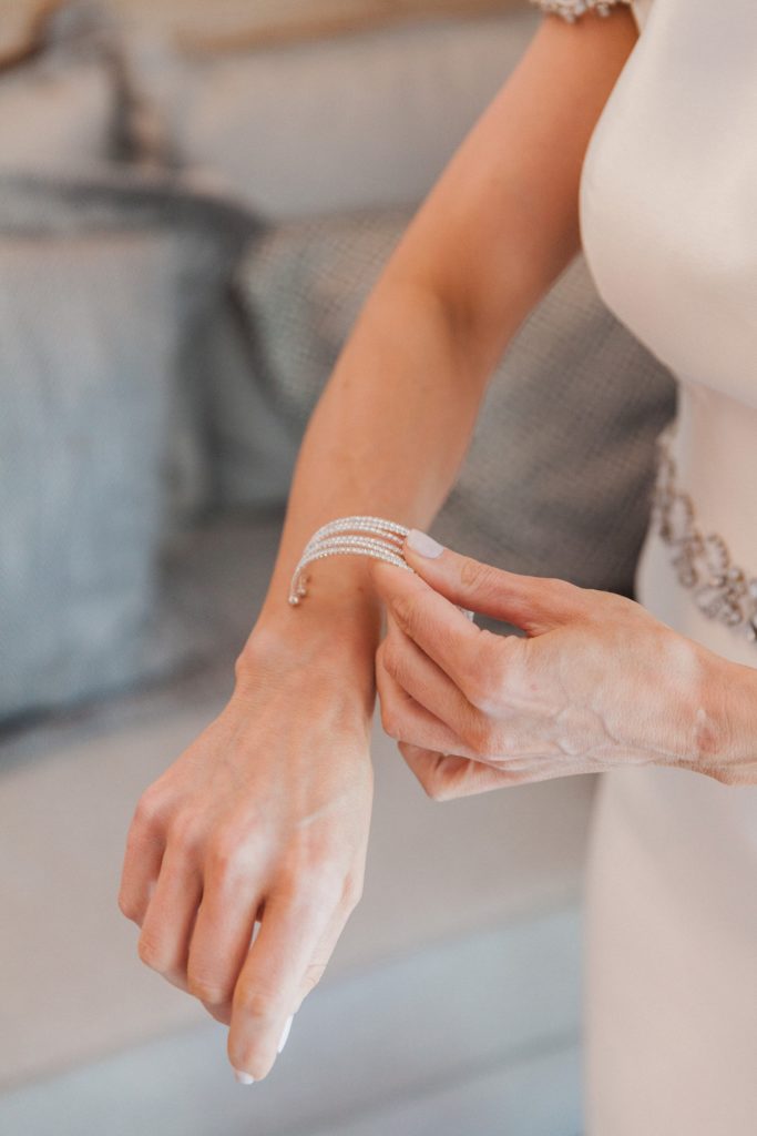 Detail image of a bride putting on her diamond bracelet