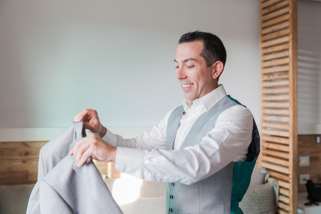 Groom smiles as he dresses in a Ted Baker suit on his wedding day