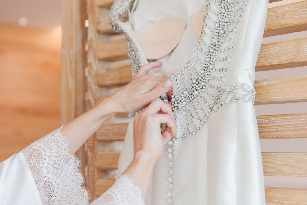 Bride undoes the buttons on her Rosa Clara wedding dress before putting it on