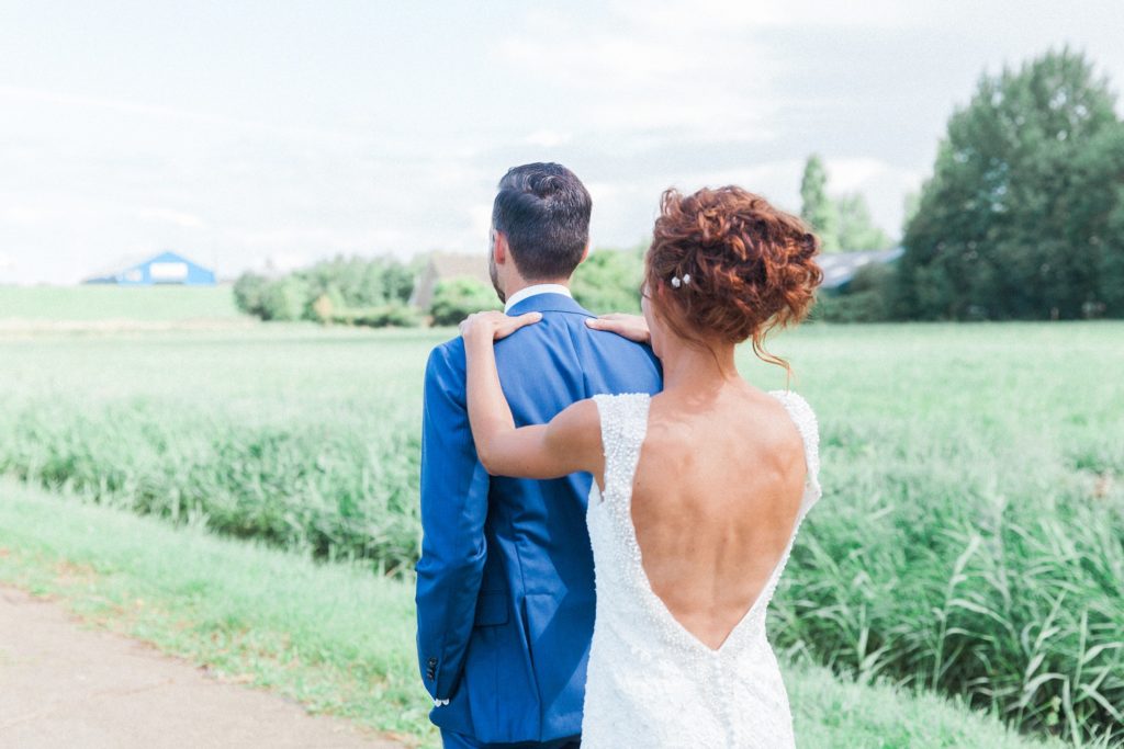 Bride reaches out to touch the grooms shoulder during their first look