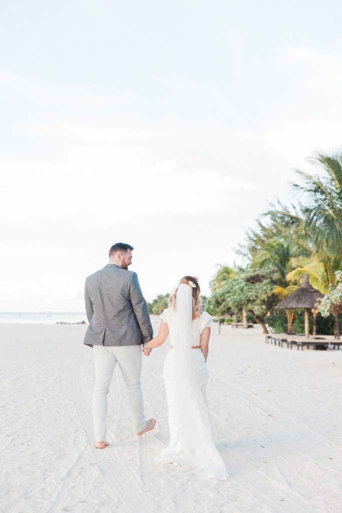 Couple walk along the beach holding hands after their destination wedding in Mauritius