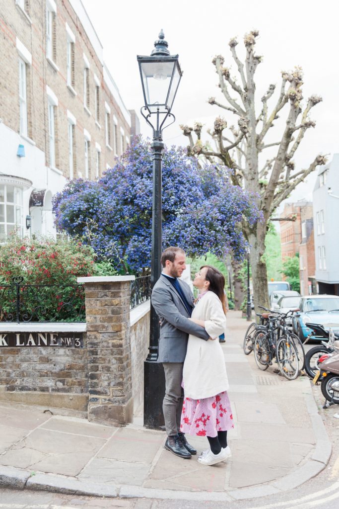 Couple hug on a pretty street corner in Hampstead Village