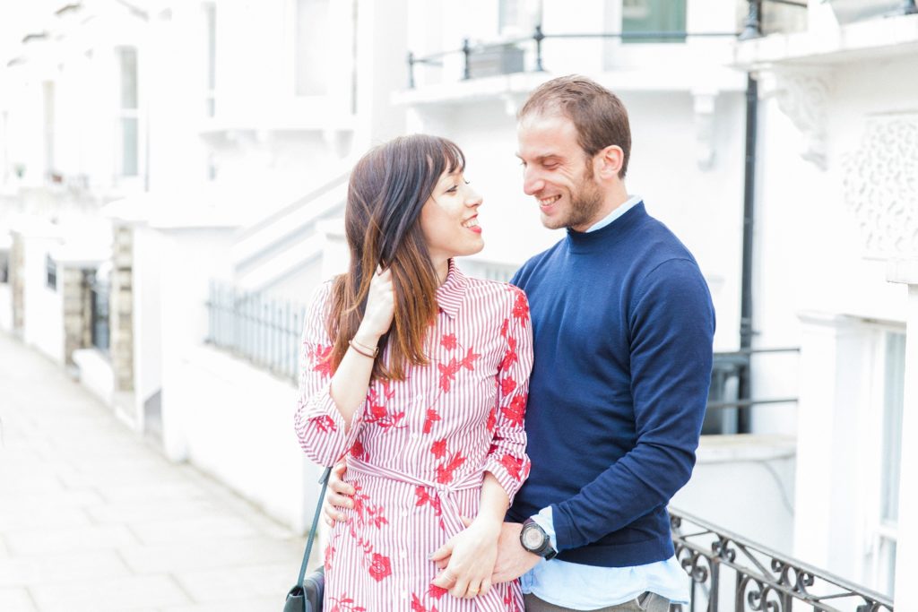 Couple smile during their engagement session on the streets of Hampstead Village