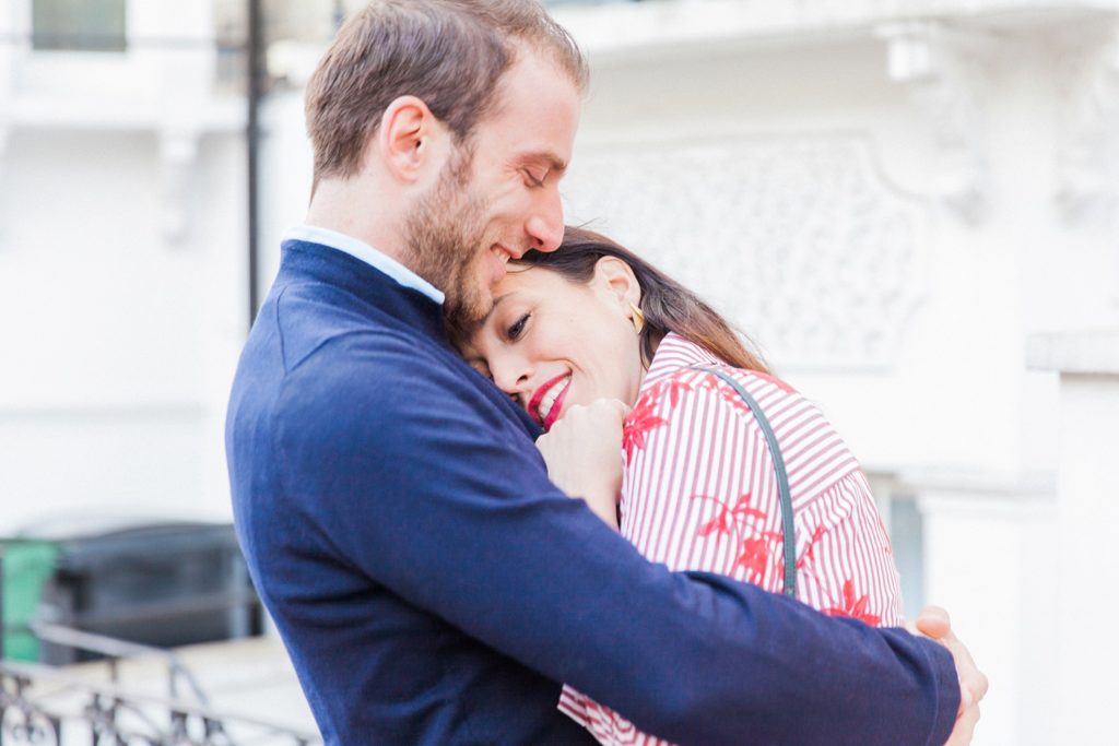 Bride to be cuddles up to her fiance during their Hampstead Village engagement session