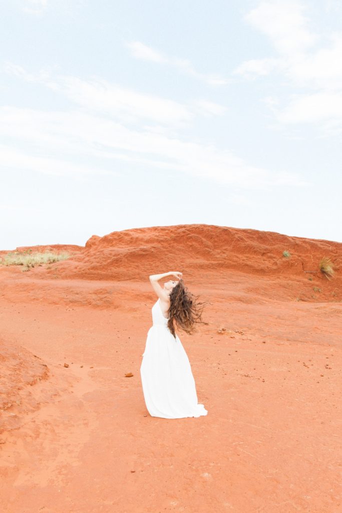 Dramatic portrait of a bohemian bride flicking her hair in the Red Desert in South Africa