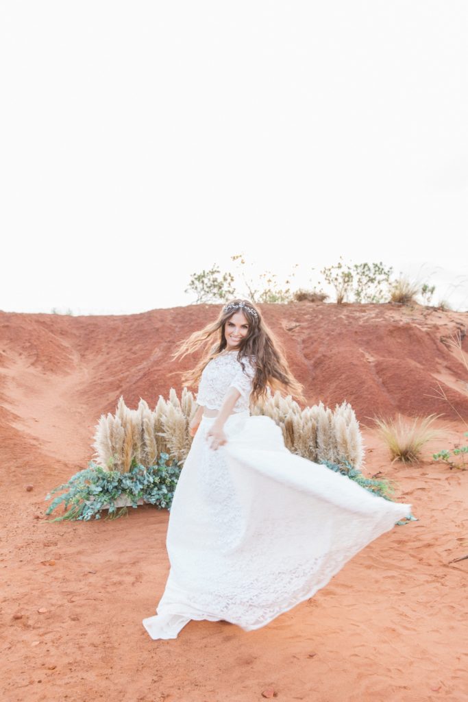 Boho bride dances in front of a pampas and eucalyptus floor arch in the Red Desert