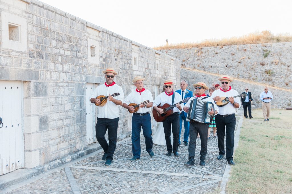 Traditional Greek band leads the bridal procession to the church inside Santa Maura Castle in Lefkada