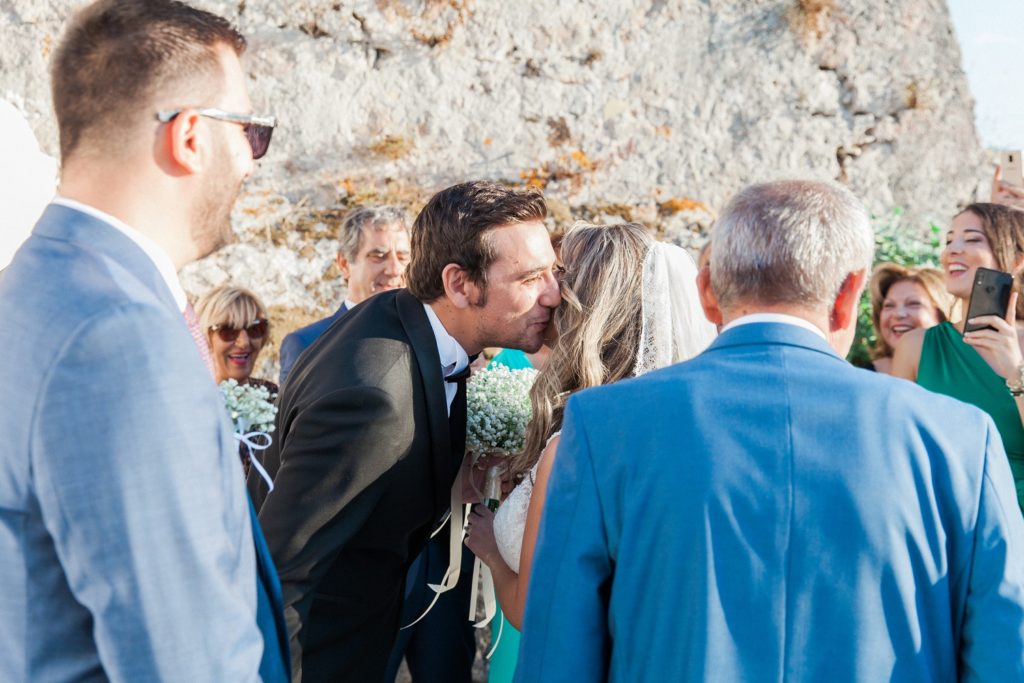 Groom kisses the bride as she arrives at the church inside Santa Maura Castle