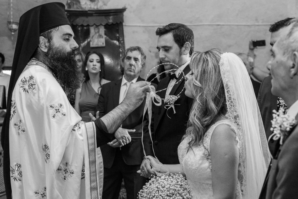 Bride kisses the stefana or Greek wedding crowns during her ceremony in Santa Maura Castle