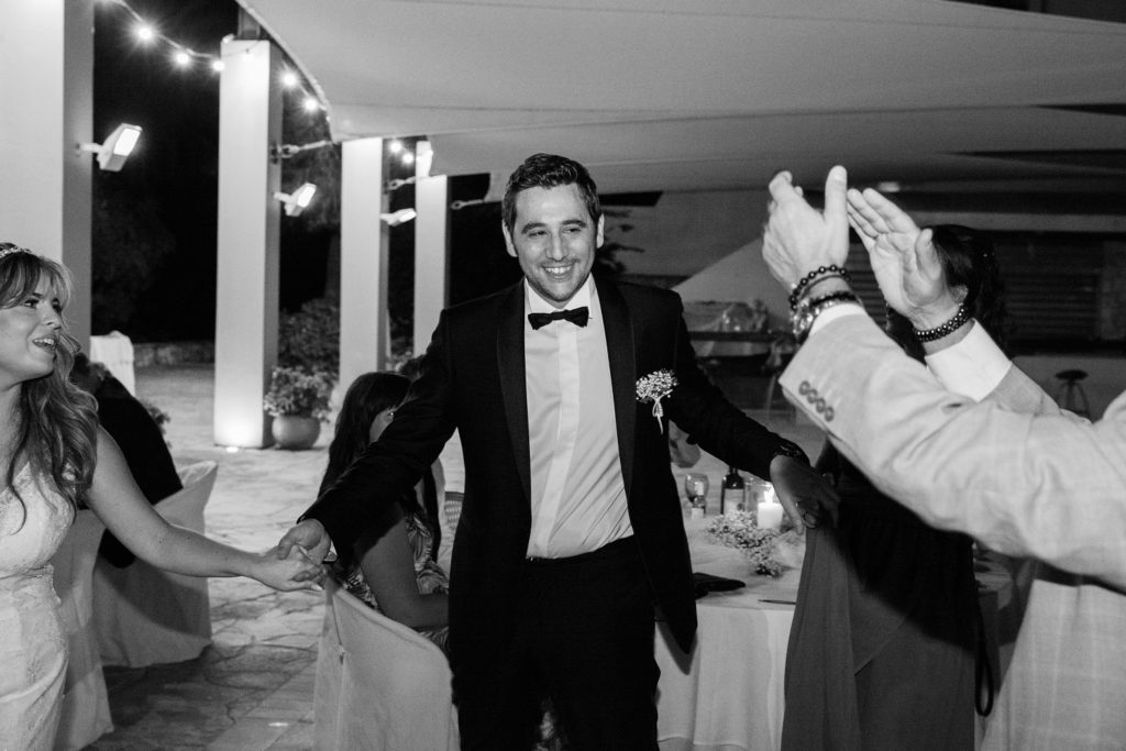 Groom smiles during the traditional Greek dancing at his Ionian Blue Hotel wedding on Lefkada