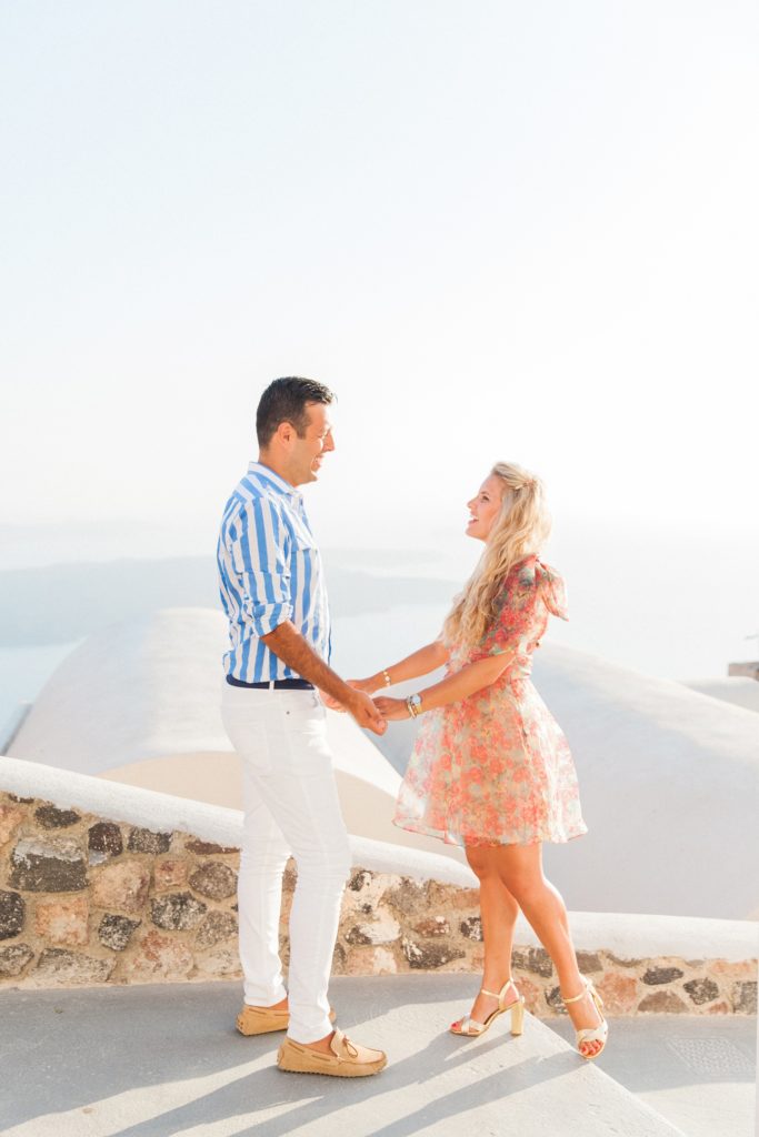 Happy couple hold hands during their honeymoon on Santorini