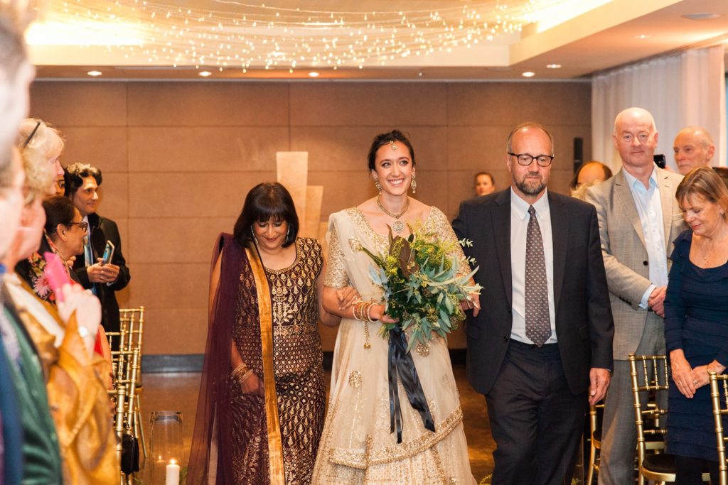 Indian bride makes her way down the aisle with her parents at her South Place Hotel wedding in London
