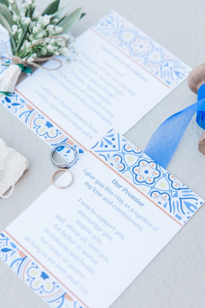Blue, white and orange wedding stationery flatlay with wedding rings
