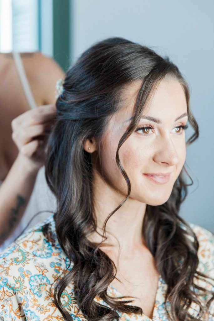 Bride smiles while she gets her hair done on the morning of her elopement