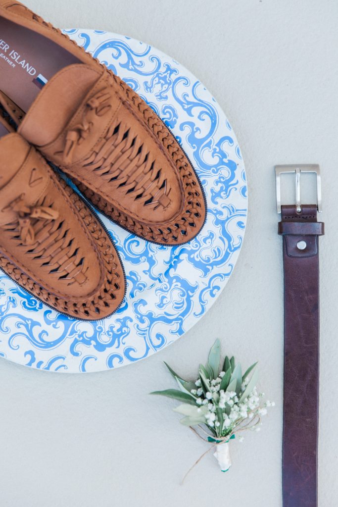 Flatlay of the grooms details including shoes, belt and buttonhole