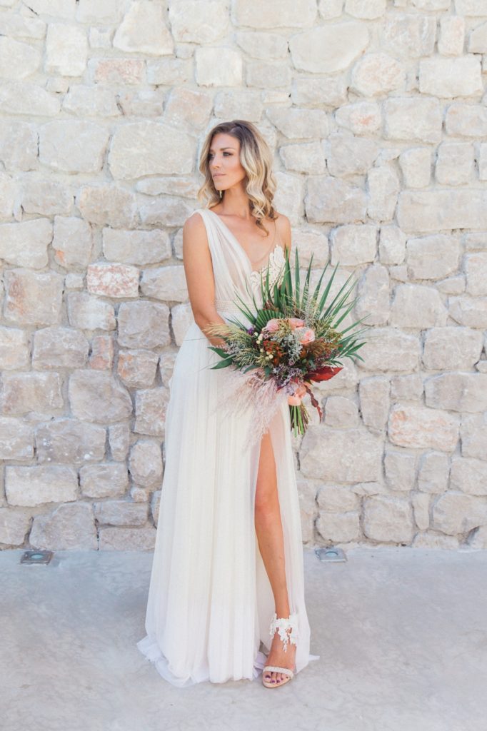 Bride poses in an Atelier Zolotas wedding dress and boho bridal bouquet