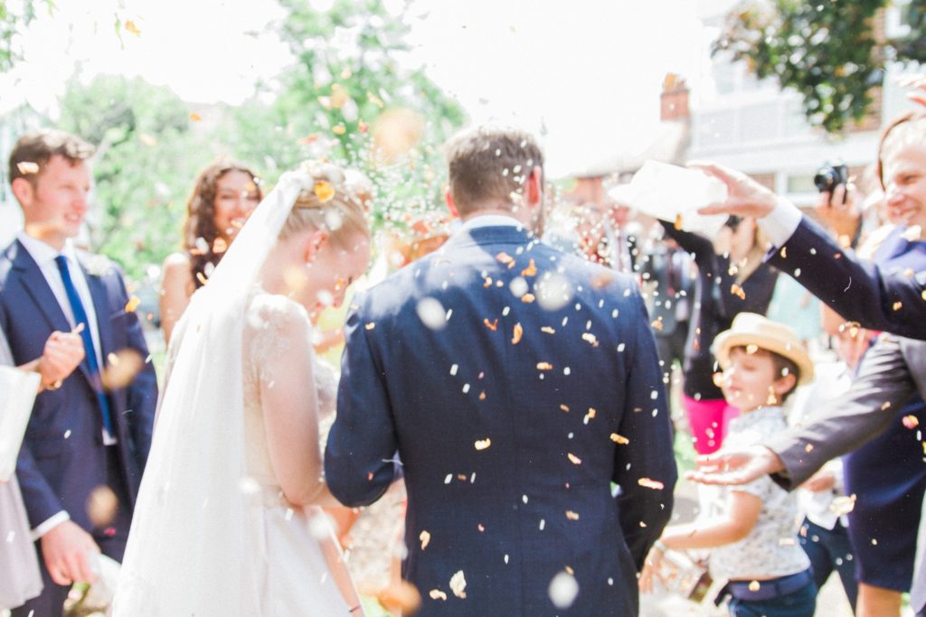 Couple walk through a shower of confetti on their wedding day