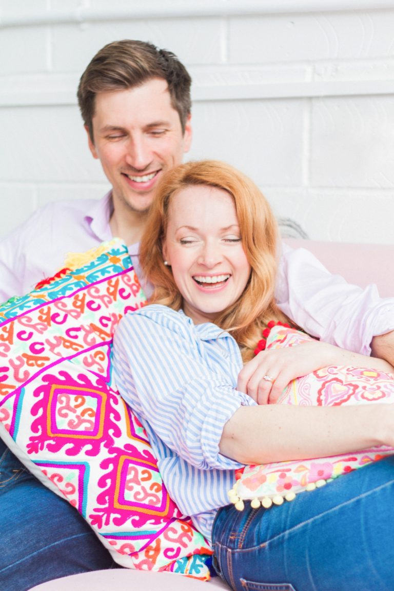 Couple sitting on the couch sharing a laugh during their engagement session