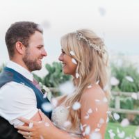 Bride and groom embracing under a shower of confetti on Kefalonia