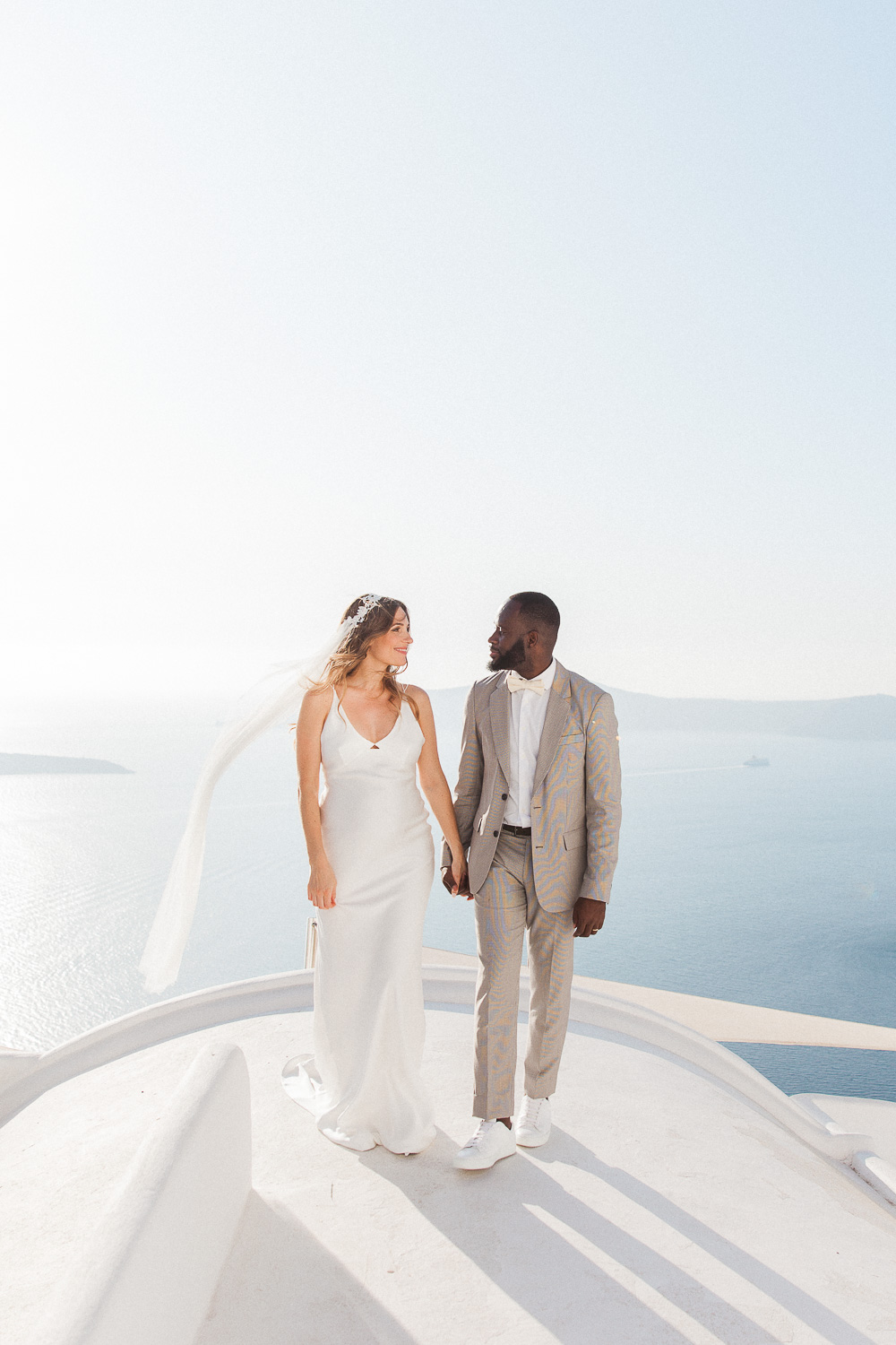 Bride and groom walking on a Santorini rooftop on their wedding day
